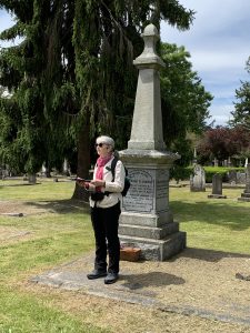 Yvonne standing at the grave of Amor de Cosmos