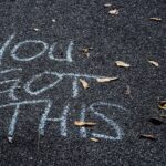 The Words "You Got This" Written In Chalk On The Ground, With A Few Fallen Leaves Strewn Around